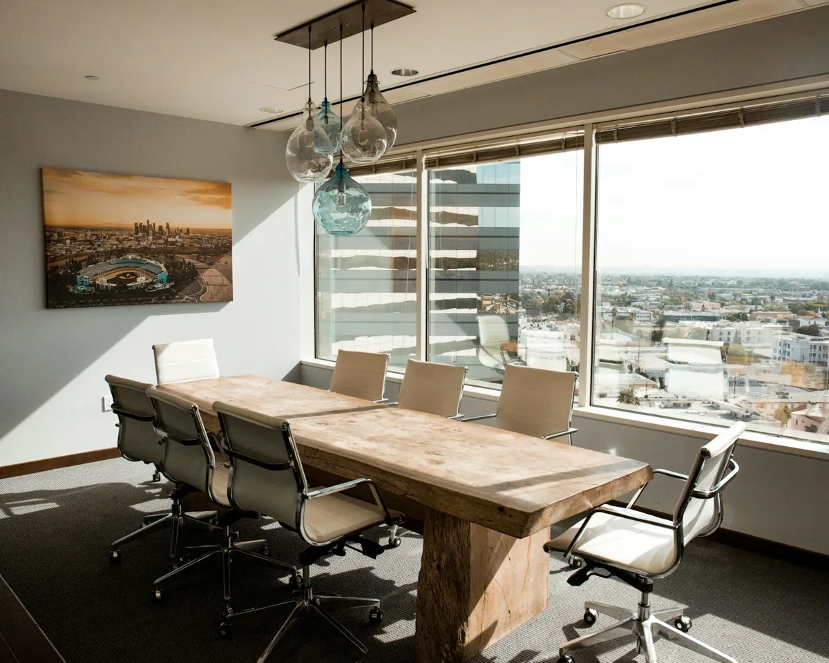 An empty meeting room with a wooden conference table, office chairs and pendant light fittings.