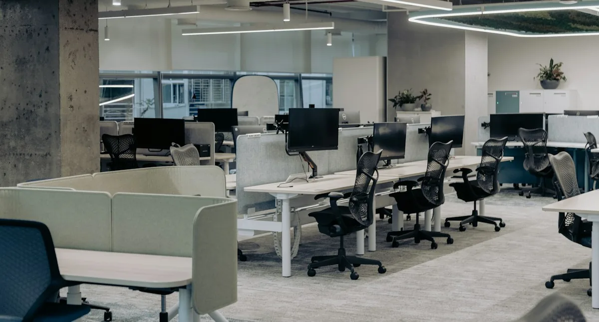 Open office desks with upholstered dividers and soft shared seating.