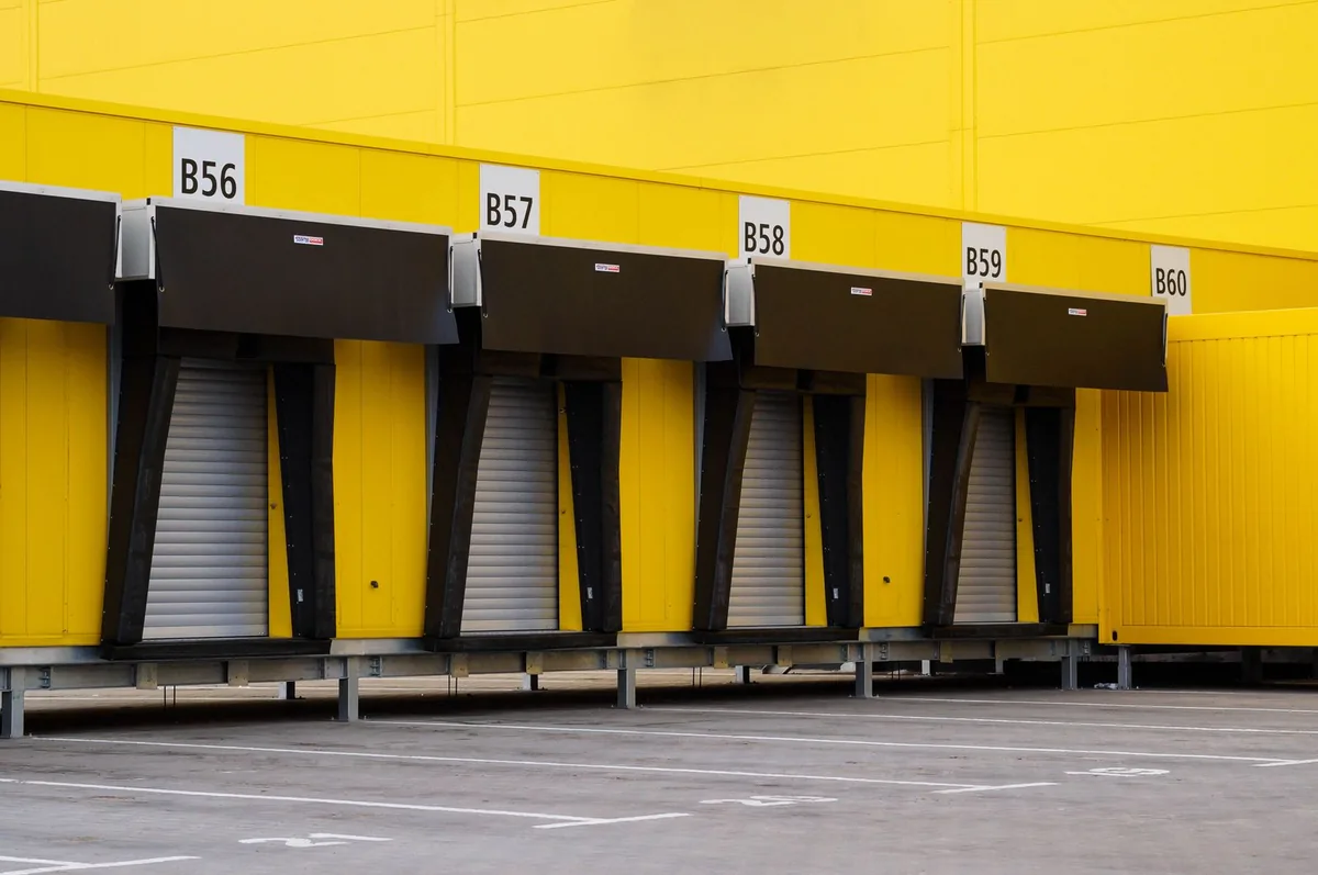 Numbered loading docks and marked vehicle approaches outside a yellow warehouse.