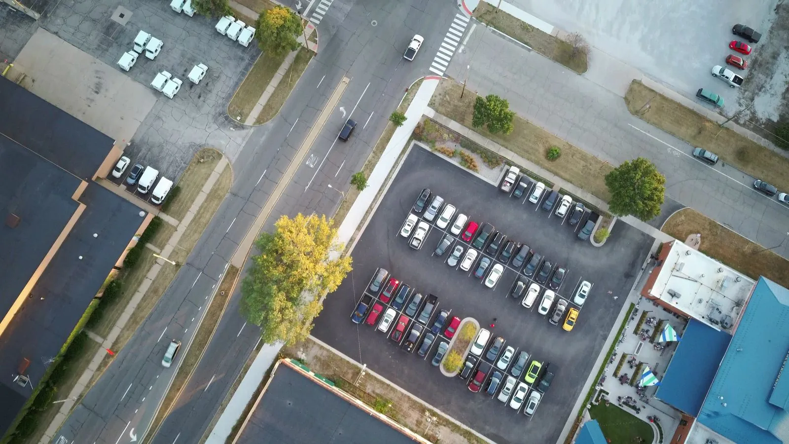 Aerial view of cars in marked parking bays beside an urban intersection.