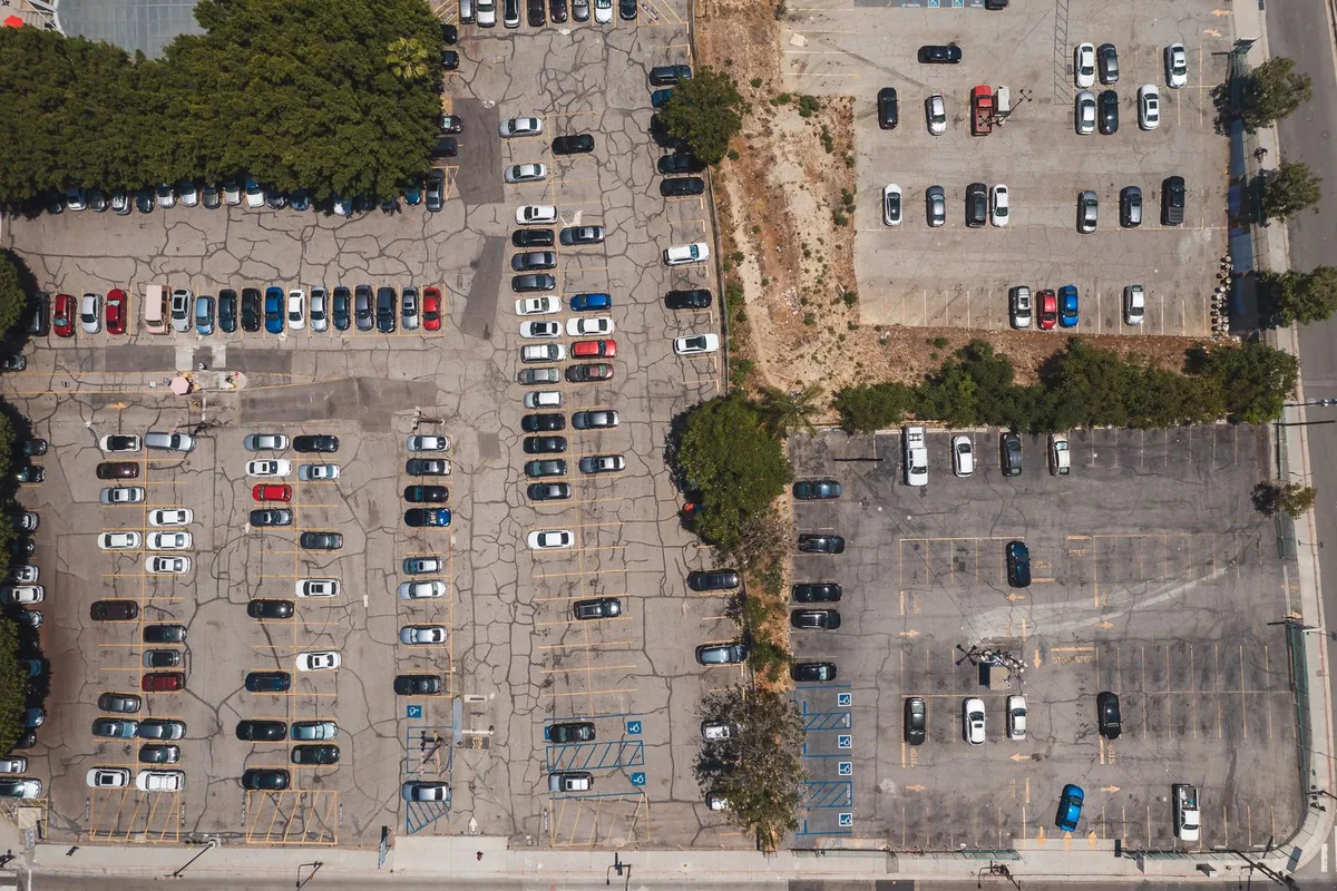 Overhead view of cars arranged in marked rows across a large parking lot.