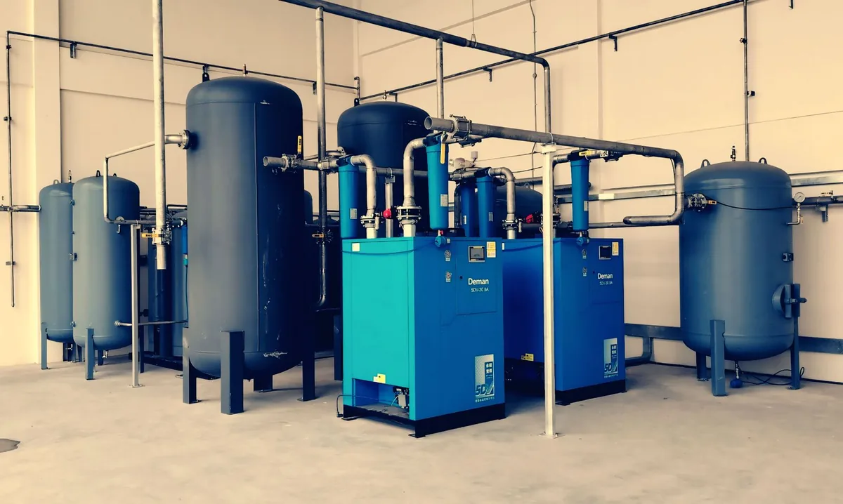 Blue industrial pressure vessels, filtration units and connecting pipework in a plant room.