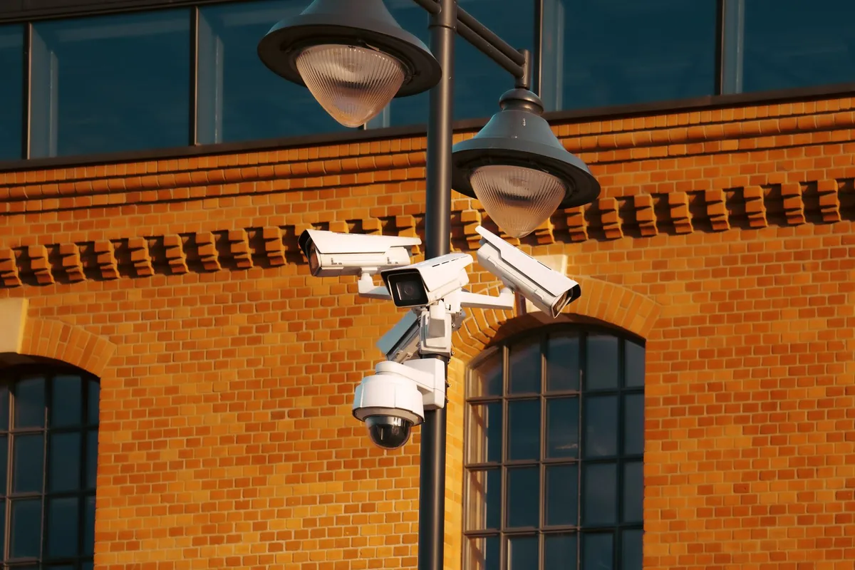 Surveillance cameras mounted on a pole outside a brick building.