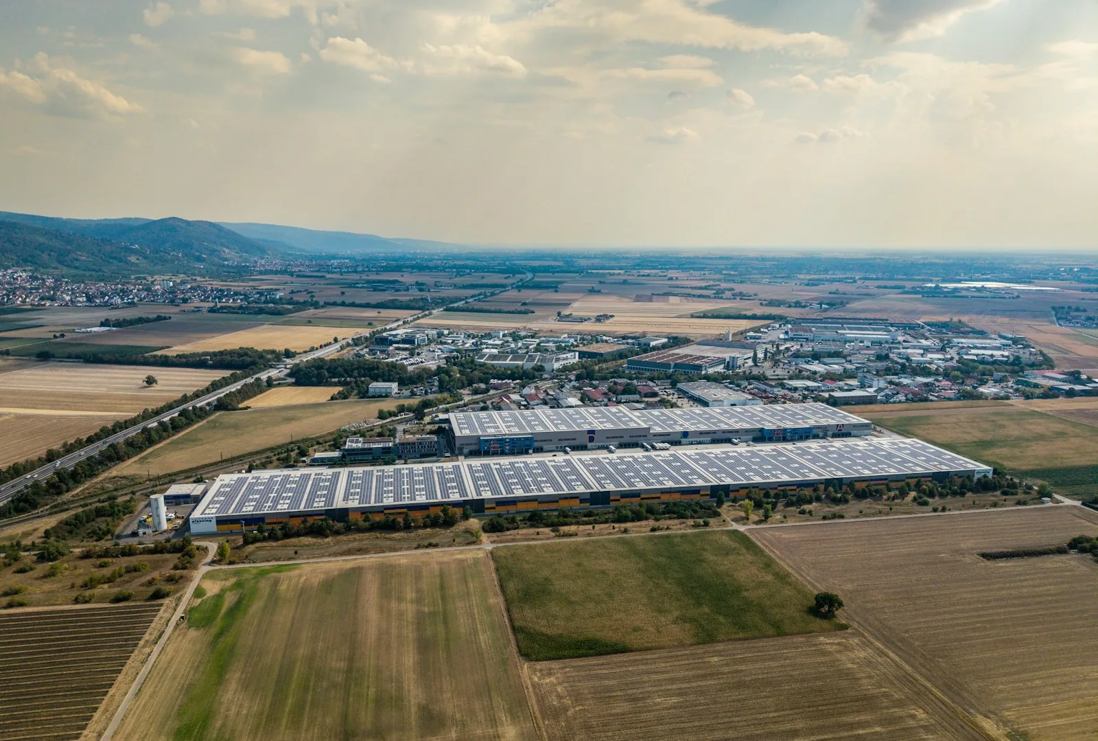 Aerial view of a large warehouse with solar panels covering its roof.