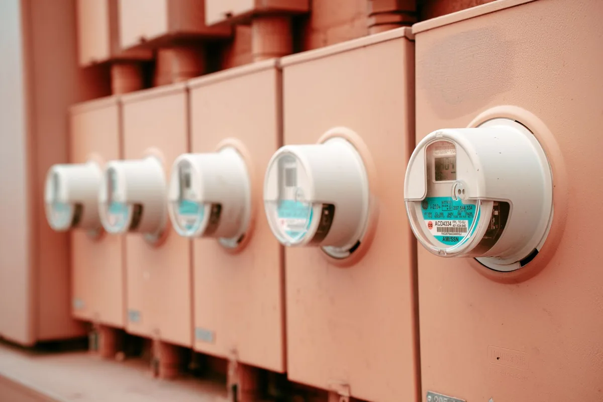 A row of round electricity meters mounted on metal service cabinets.