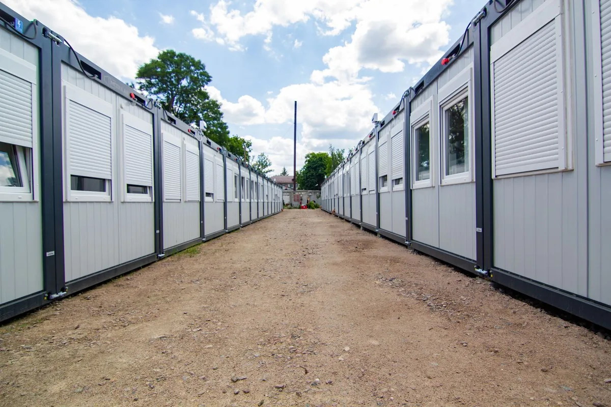 Two rows of portable site office buildings beside a dirt walkway.