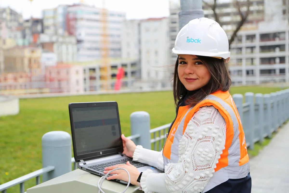 Engineer using an open laptop at an outdoor construction site.
