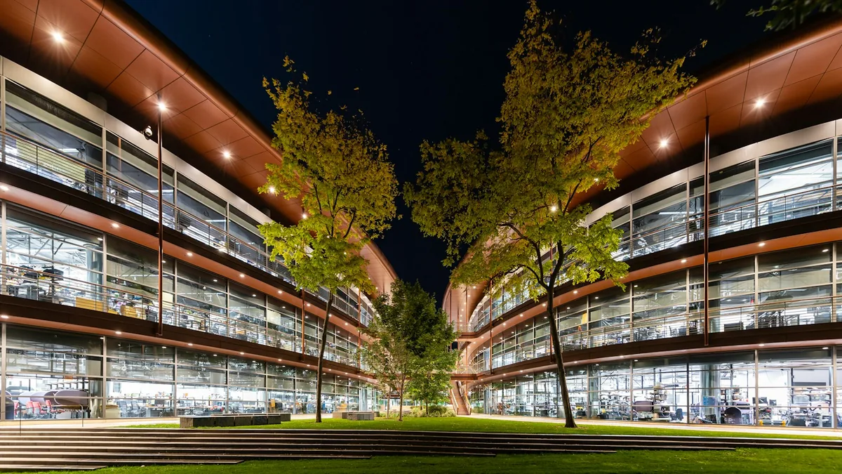 Illuminated campus buildings around a landscaped courtyard at night.