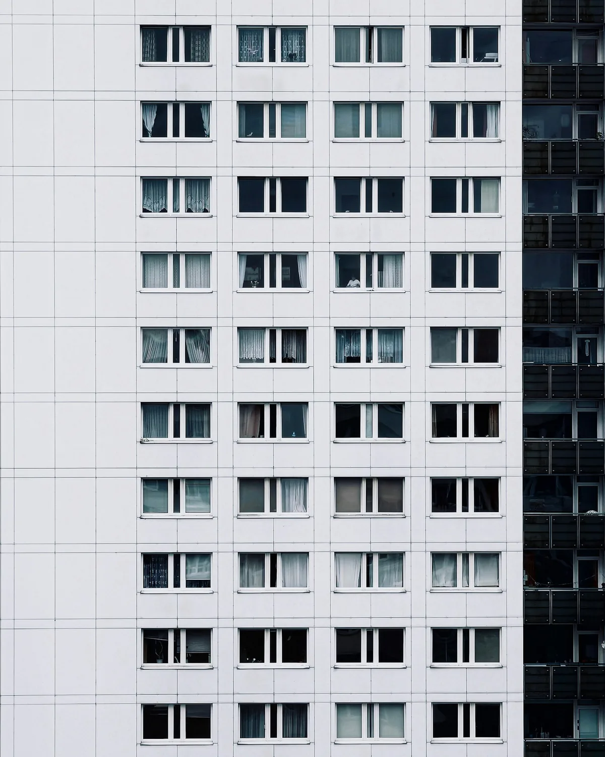 Repeated apartment windows in a white multi-unit building facade.