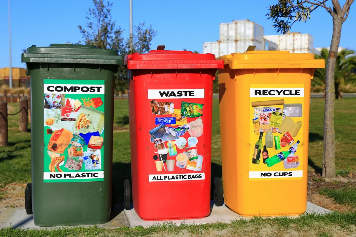 Green, red and yellow waste-sorting bins on a paved outdoor path.