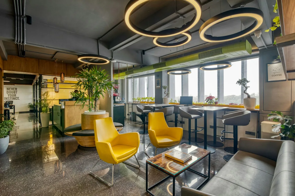 A shared workplace lounge with yellow chairs, sofas and high tables.