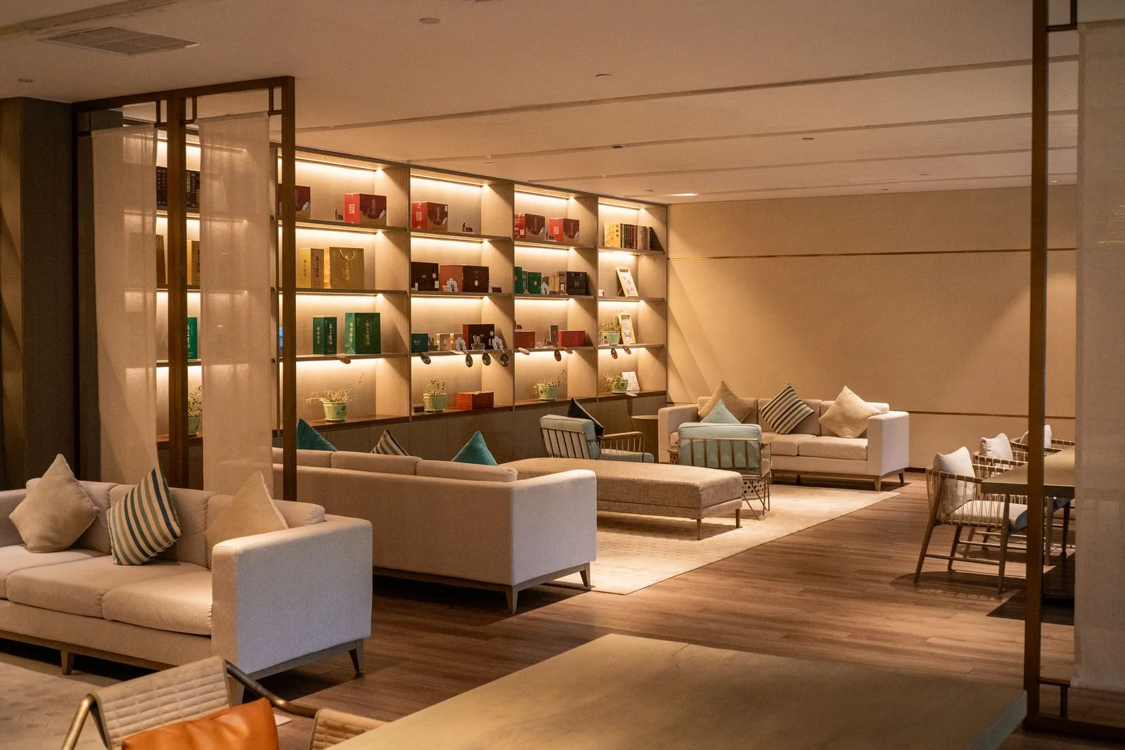 Hotel lounge with upholstered seating, small tables, and illuminated bookshelves.