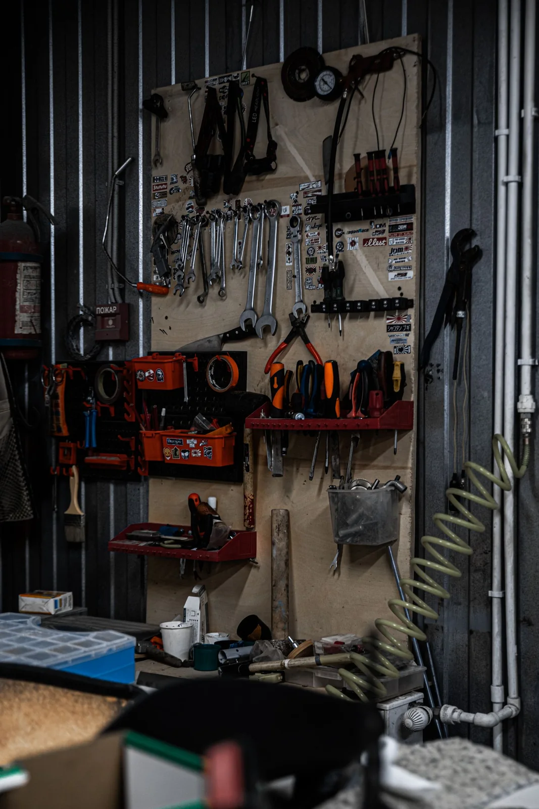 Workshop tool station with hand tools hanging on a wall above a work surface.