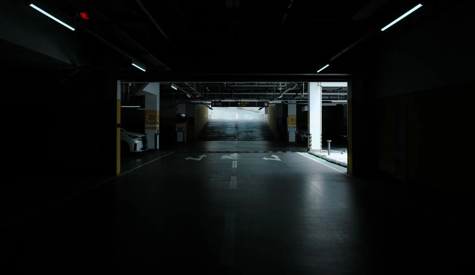 Dim underground parking area with an illuminated ramp leading upward.