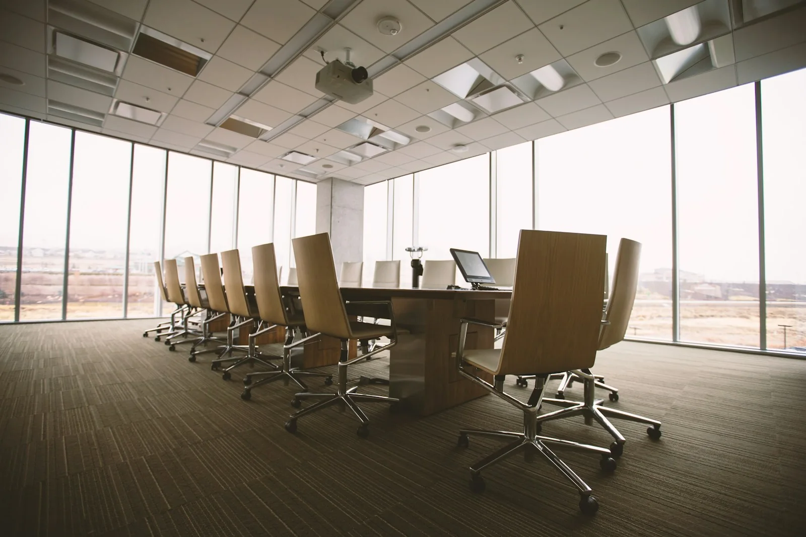 An empty meeting room with a long table, chairs and ceiling air diffusers.