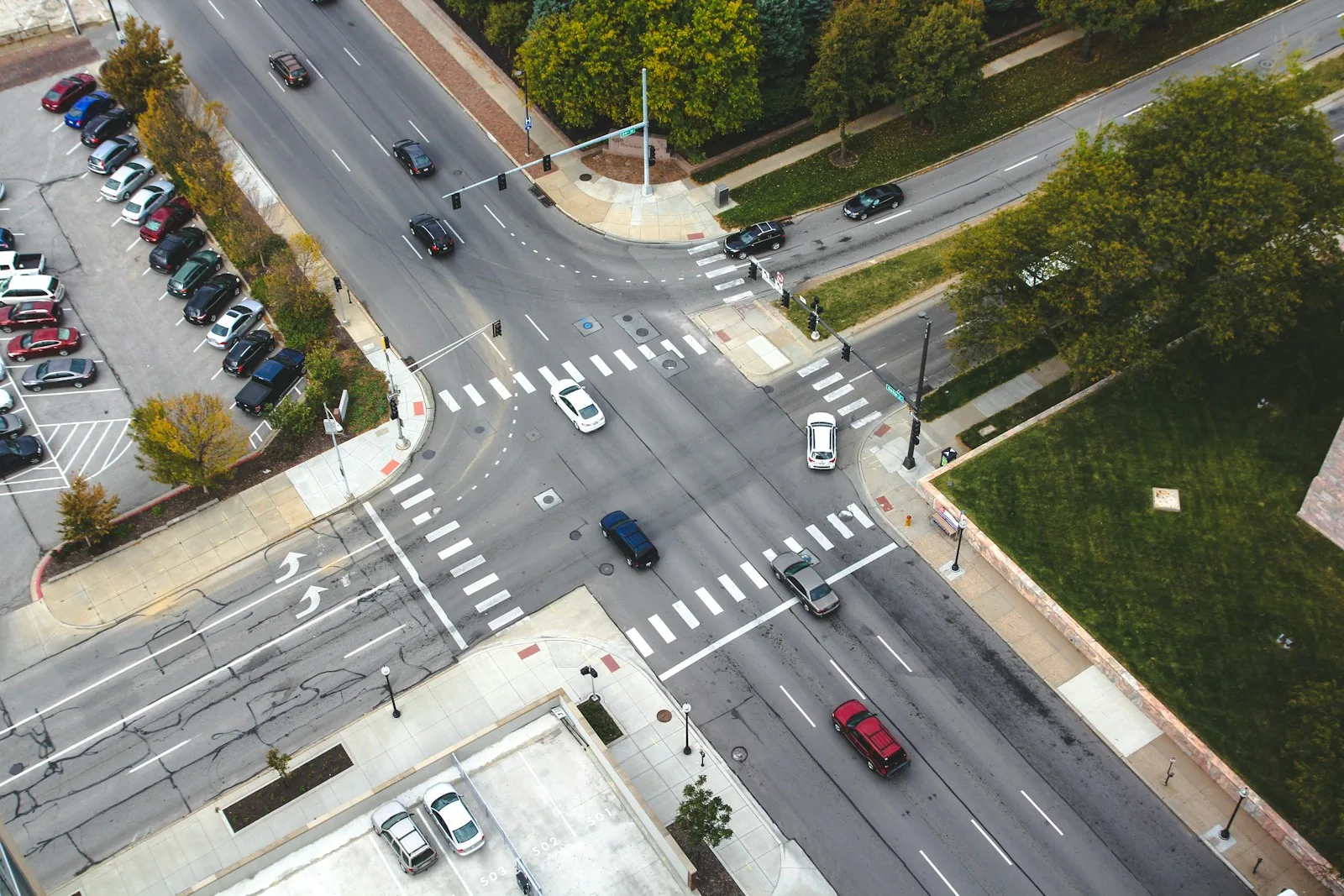 Elevated view of cars, crosswalks and turn markings at an urban intersection.