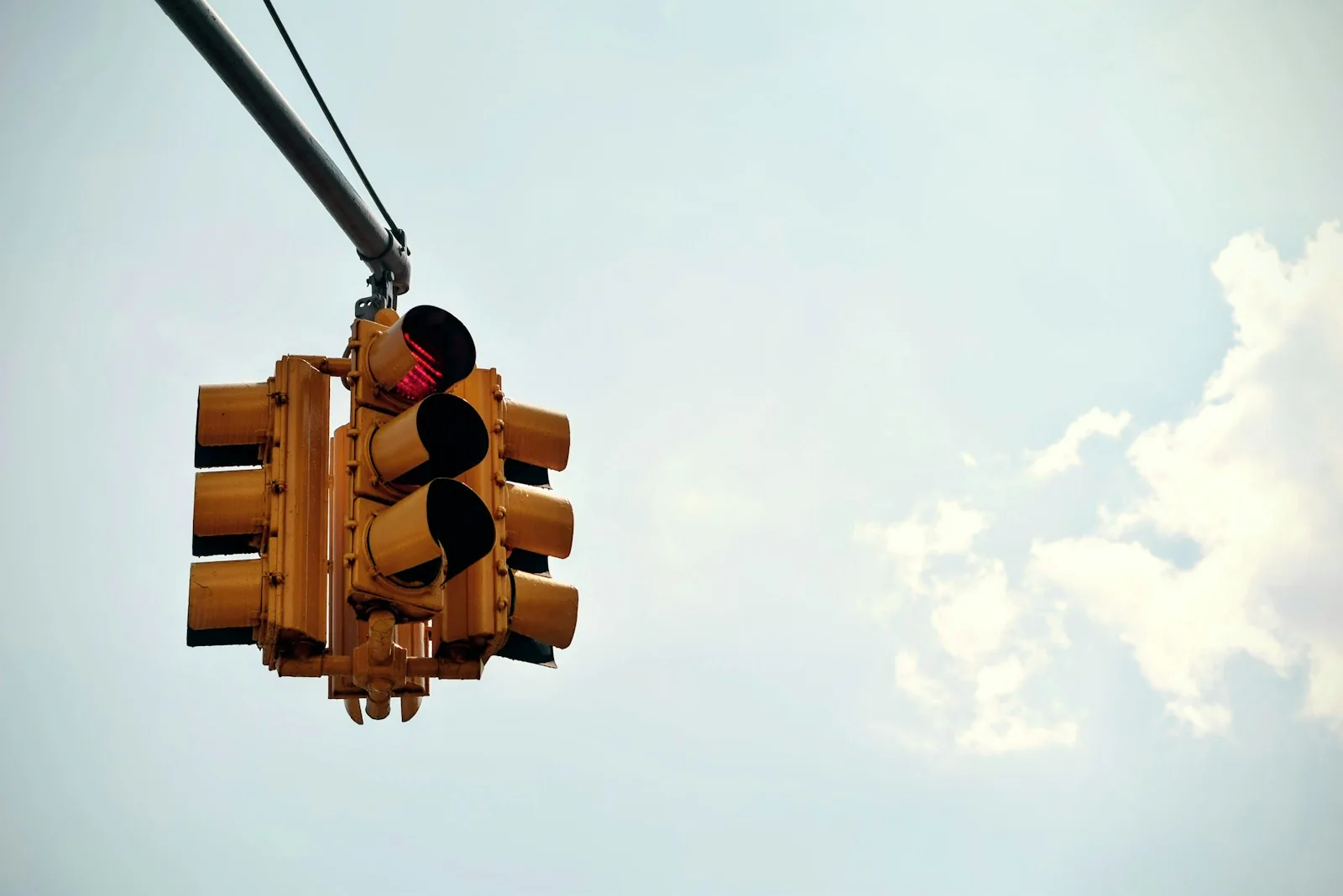 A suspended yellow traffic signal with its red light illuminated.