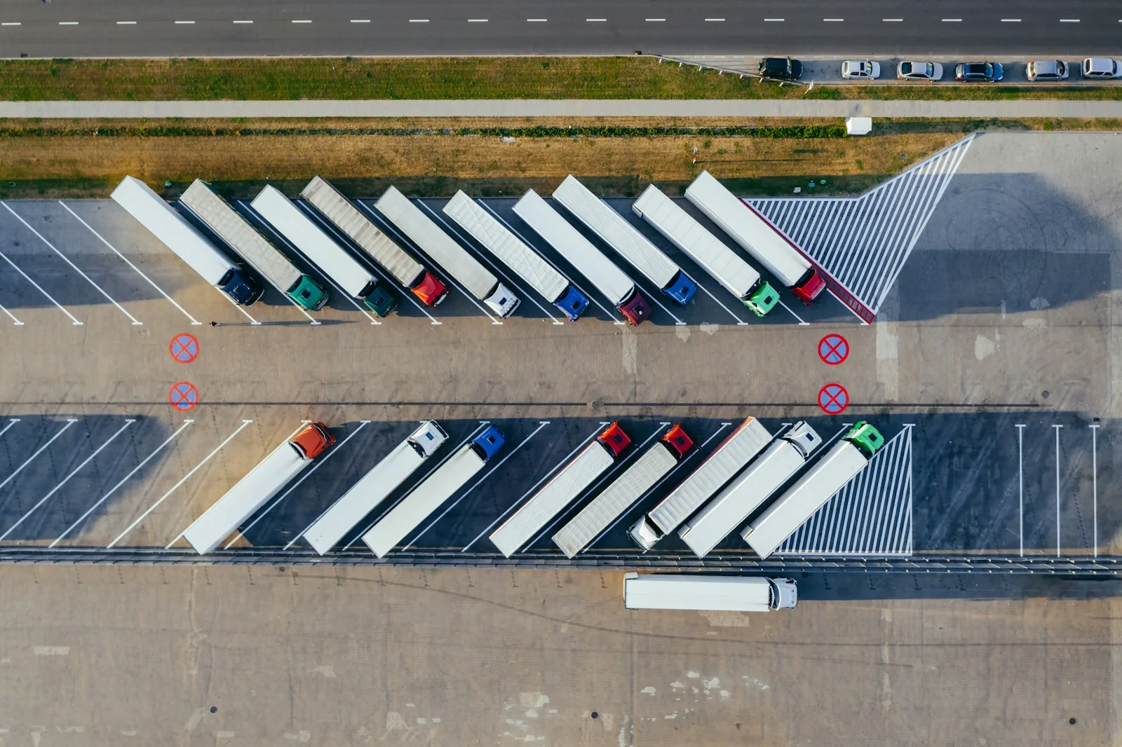 Overhead view of parked tractor-trailers and marked circulation space at a logistics site.