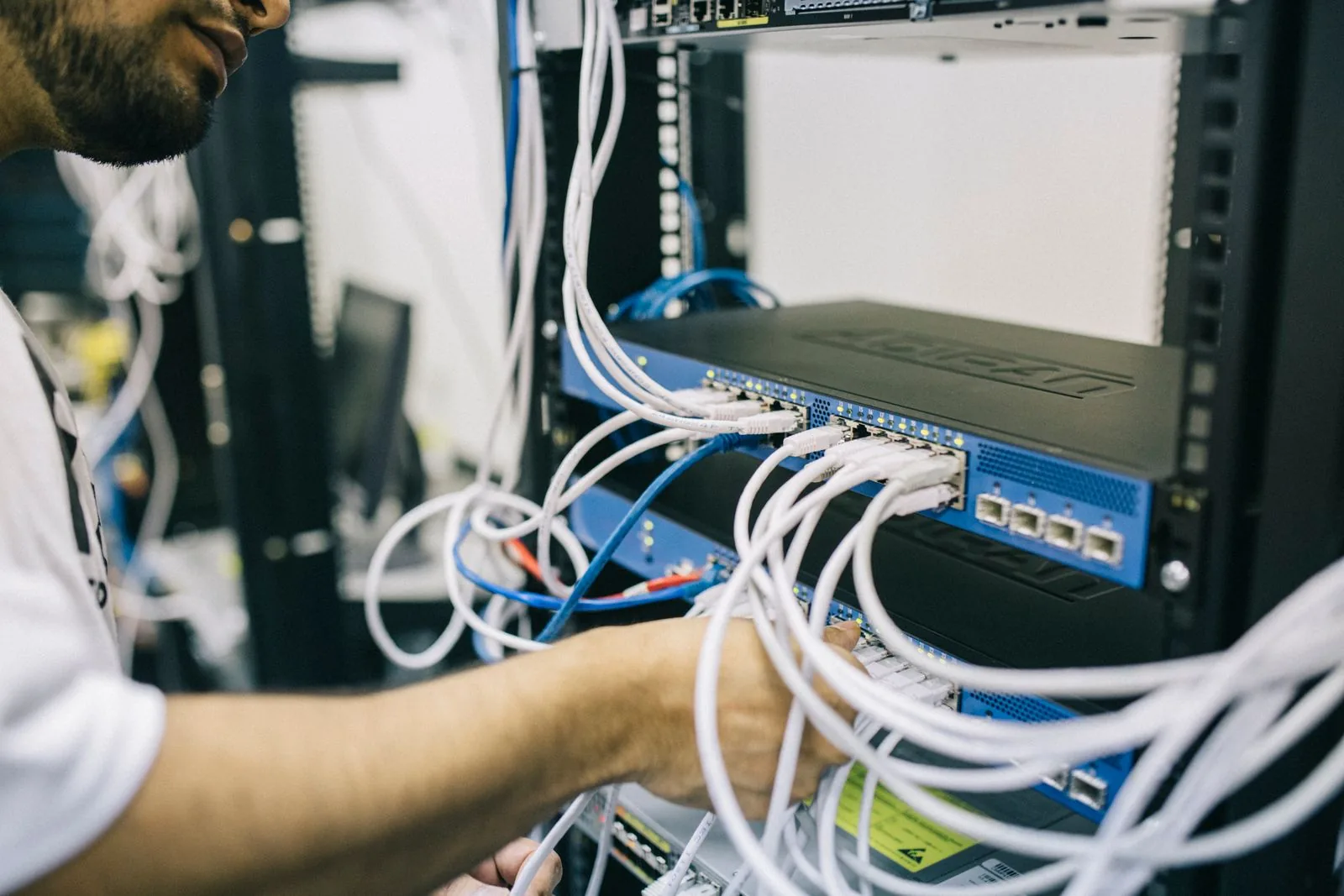 A technician working on Ethernet cabling in a network rack.