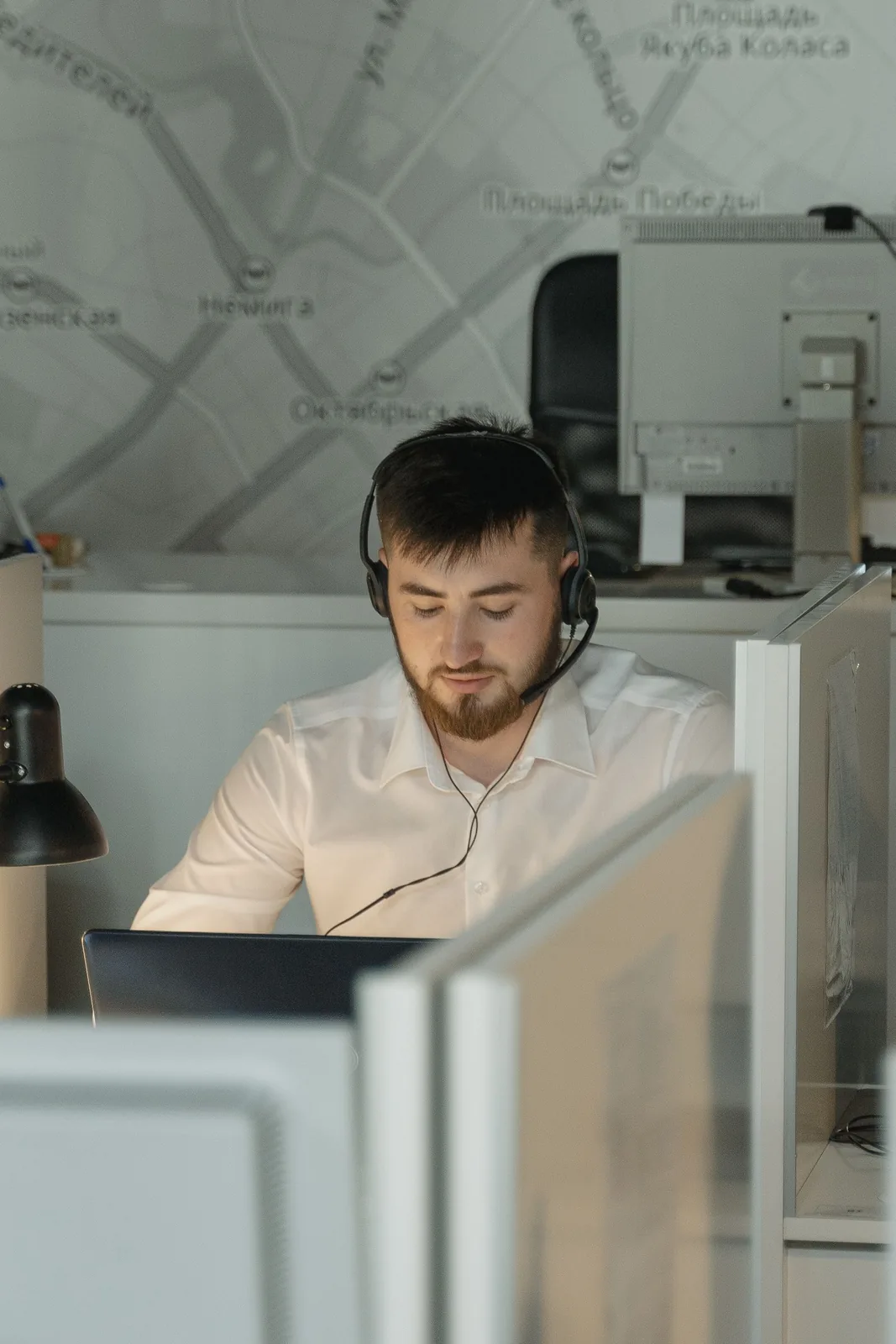 A man wearing a headset while working at an office computer.