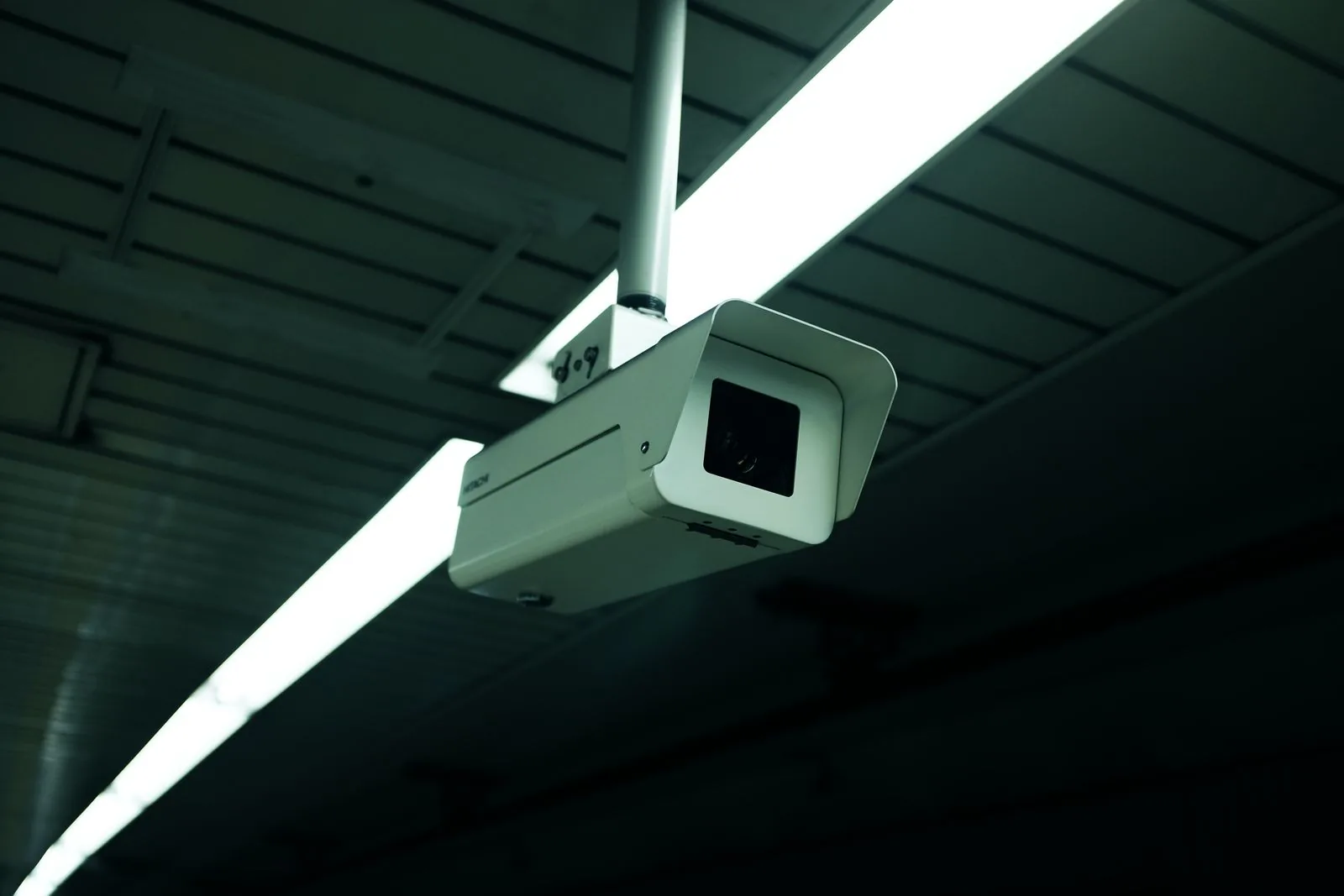 A ceiling-mounted box security camera beneath a strip light.