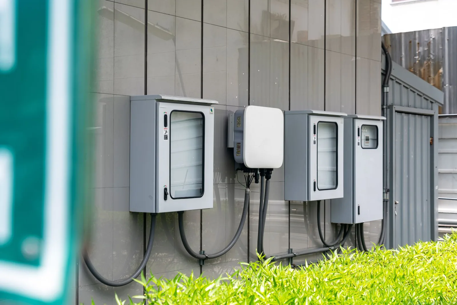 Closed electrical service enclosures and cabling mounted along an exterior wall.