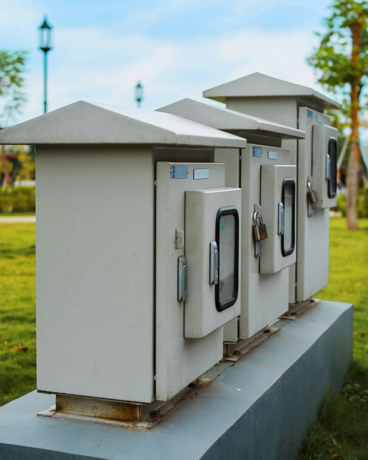 A row of gray electrical service cabinets outdoors on a raised concrete base.
