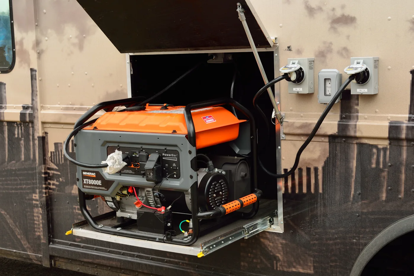 A portable generator standing upright on a slide-out platform at the side of a vehicle.