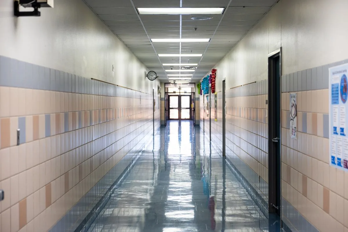 Empty school corridor with tiled walls, classroom doors and a polished floor.