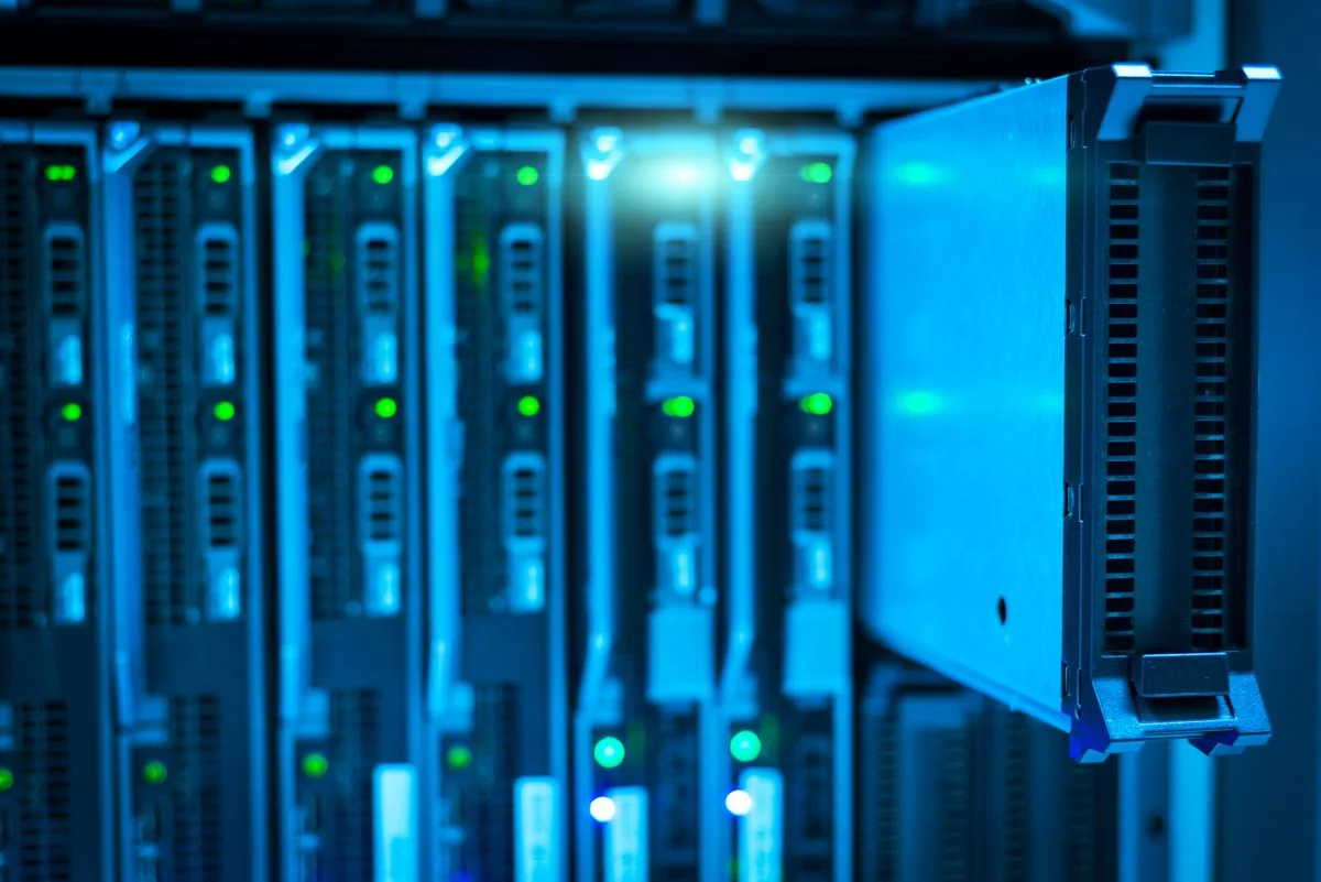 A partially withdrawn server module beside a row of equipment with green status lights.
